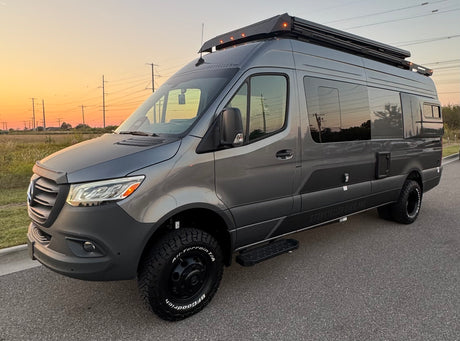 Grey Storyteller Overland campervan, ideal for an rv rental adventure, captured at sunset with rugged off-road tires.