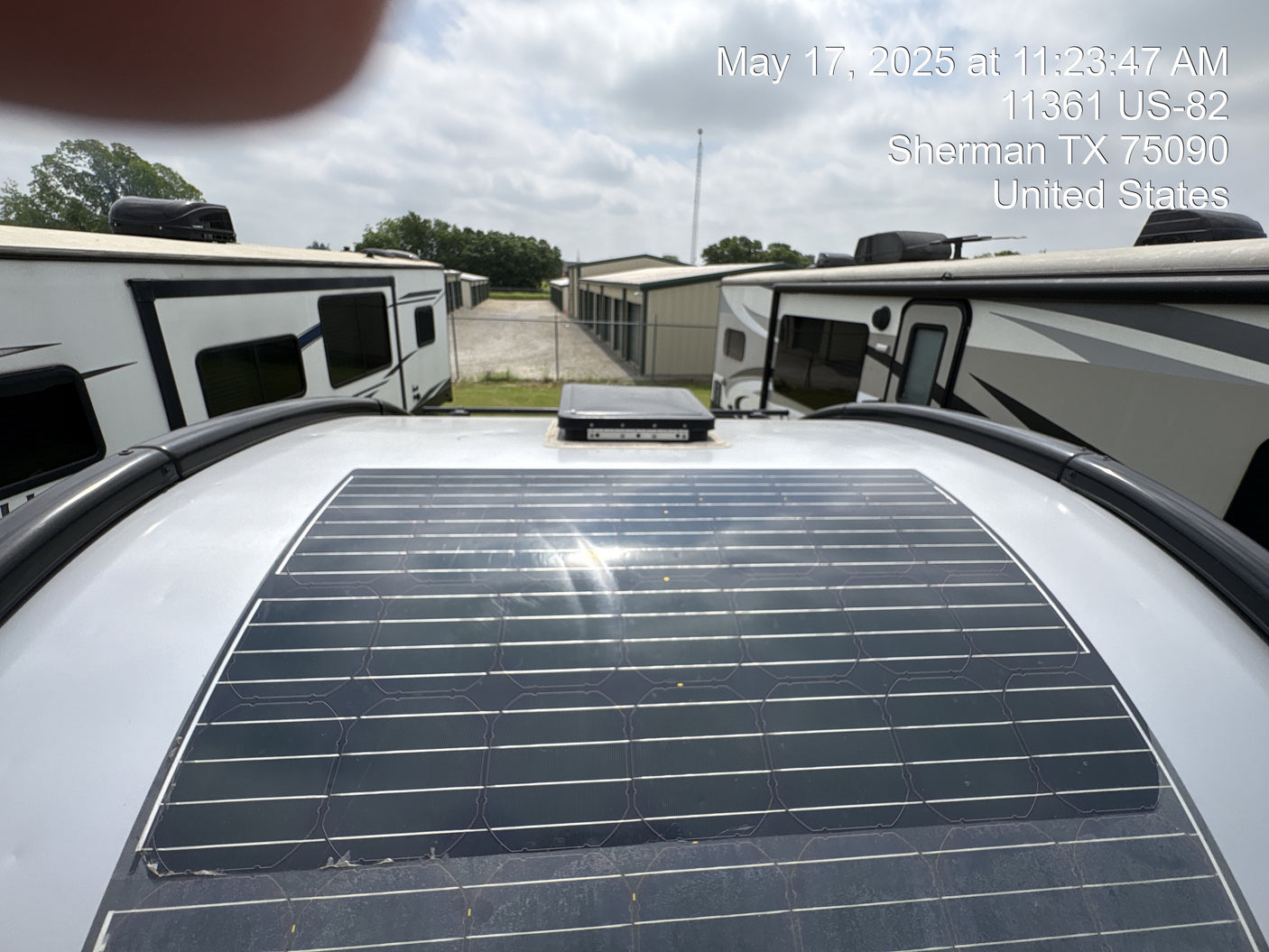 An RV rental, featuring a rooftop solar panel, parked among other RVs near storage units in Sherman, Texas.