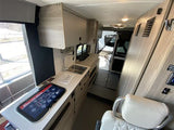 Modern rv rental interior: compact kitchen, embedded display, and swiveling seat for comfortable van life adventures.