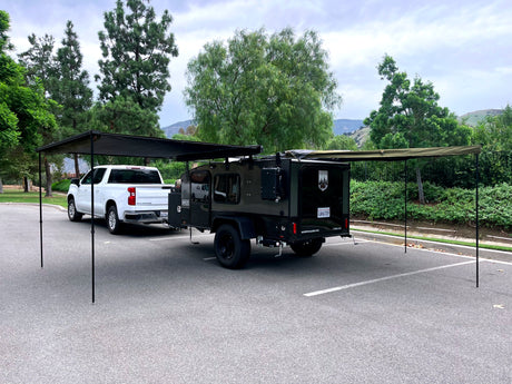 This rv rental setup showcases a white pickup truck towing a Hiker teardrop camper with extended awnings for shaded outdoor adventure.