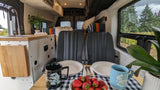 Inside a comfy RV rental: Enjoy breakfast with fresh strawberries, coffee, and a picturesque view of the trees outside.