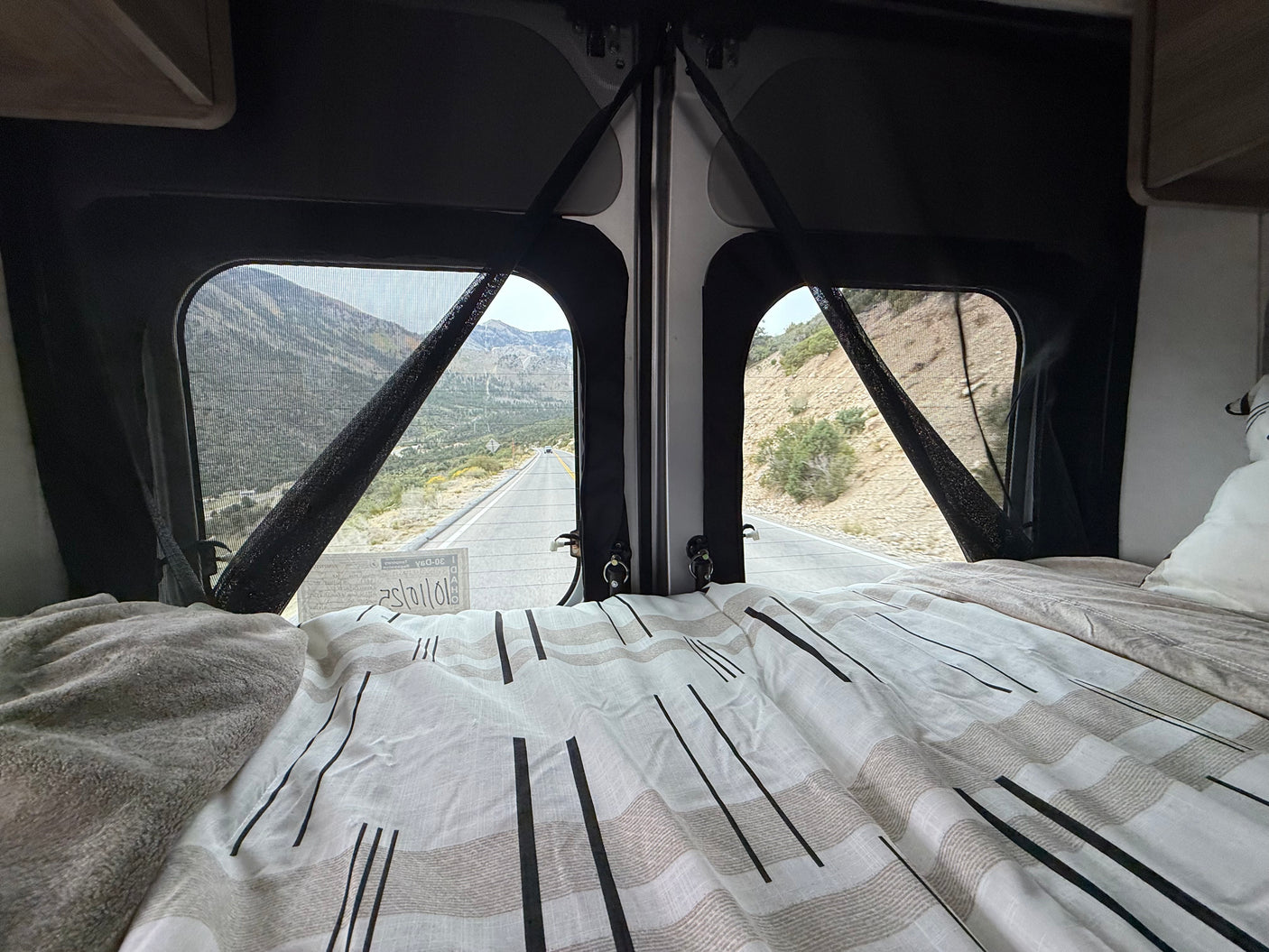 Cozy RV rental view: mountain road from the bed. Perfect for a scenic road trip adventure, seen from inside an RV.