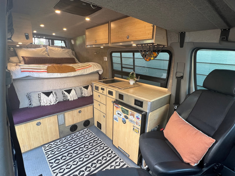 This RV rental camper van features a cozy bed, kitchenette, custom storage, and a modern interior design. — photo 14