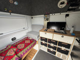 Compact rv rental interior featuring a kitchenette, bed, and smart labeled storage for organized travel adventures.