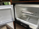 Inside an open Norcold RV refrigerator, showing clean shelves, ice cube trays, and a plastic bin. Ideal for your rv rental.