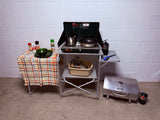 This complete portable camping kitchen, featuring a Coleman propane stove, Cabela's grill, and utensils, is ideal for any RV rental.
