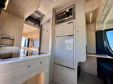 Modern RV rental interior: kitchenette with fridge/microwave, sleek design, and compact workspace for mobile living.