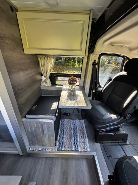 Cozy rv rental interior: dinette with swivel seat, window view, and compact amenities for comfortable travel.