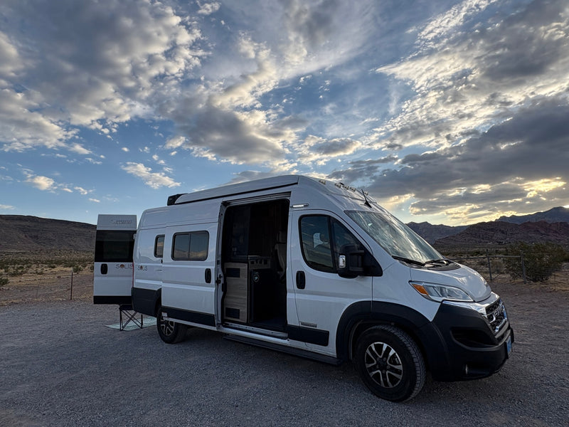  and mat in a desert mountain landscape.|White Winnebago Solis RV rental parked in desert with open doors — photo 14