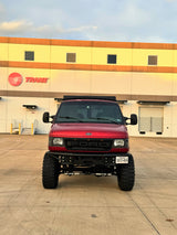 Custom red Ford adventure van, ideal for an rv rental, parked at a Trane facility in Texas.