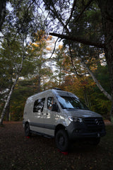 Adventure awaits with this sleek Mercedes Sprinter rv rental, nestled in a vibrant autumn forest. Perfect for nature exploration.