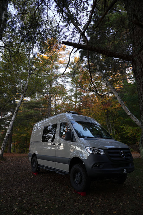 Adventure awaits with this sleek Mercedes Sprinter rv rental, nestled in a vibrant autumn forest. Perfect for nature exploration.