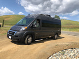 This dark grey RV rental, a Jayco Swift camper van, is parked on a dirt road overlooking a vineyard.