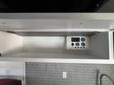 RV rental control panel: digital display, water heater, pump, fresh & gray tank gauges in overhead cabinet.