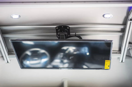 Ceiling-mounted TV with Energy Guide sticker and recessed LED lights in an RV rental interior, offering on-the-go entertainment.