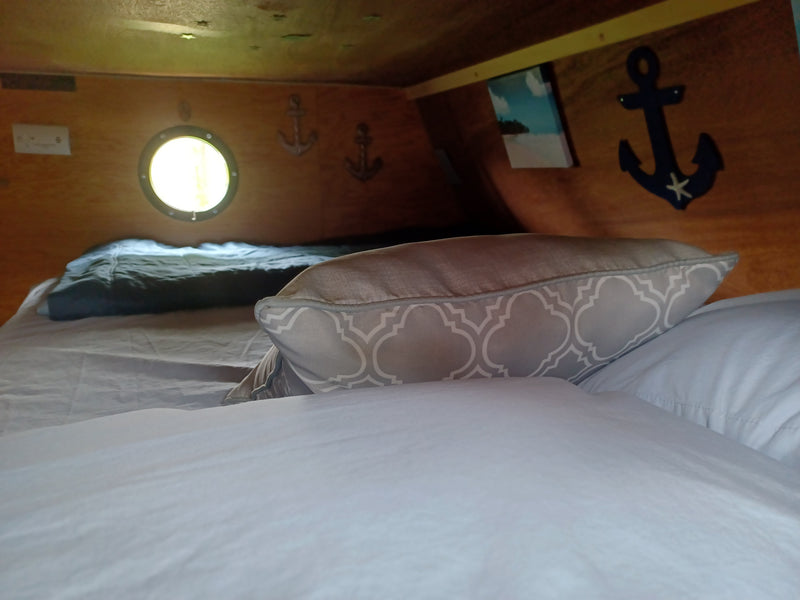 Cozy RV rental interior: bed with patterned pillow, porthole, and charming nautical decor. — photo 20