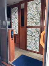 This RV rental interior features stylish wood cabinetry with peacock-patterned panels, a control panel, and a blue floor mat.