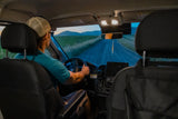 Man drives RV rental on a rural road at dusk. Seen from inside, dashboard and mountains ahead are clear.