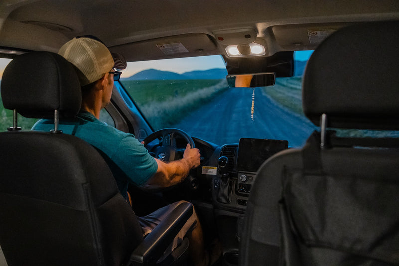  showcasing its inviting interior space & hill views.|A white pop-top camper van with open door and lit interior on a dirt road at dusk. Perfect for your next rv rental journey.|Discover adventure with this white camper van RV rental. Parked on a dirt road — photo 11