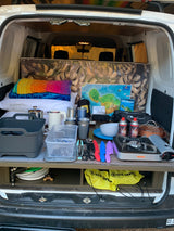 An organized rv rental camper van displays a compact kitchen setup, bedding, and travel gear for convenient camping.