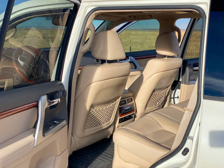 Spacious tan leather interior of an RV rental, showing comfortable seating, rear controls, and a view of open fields.