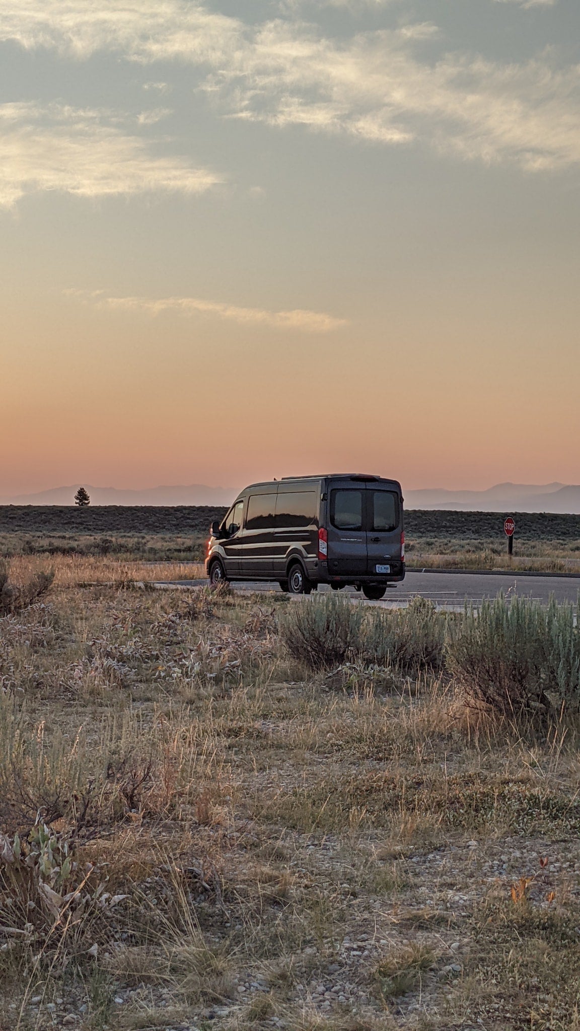 An RV rental van sits on a road at sunset