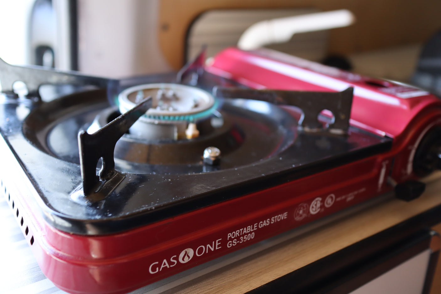 Red GAS ONE portable gas stove with a lit burner, perfect for cooking inside your RV rental. Ideal for compact travel kitchens.