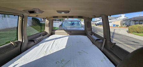 Interior of an RV rental showing a bamboo mattress set up for sleeping, with a view of a residential street outside.