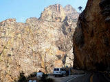 Winding mountain road trip with an rv rental. White van parked by towering rock cliffs on a scenic highway.