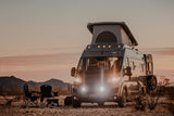 Dusk desert scene with an RV rental camper van and camping chairs. Perfect for your next adventure.
