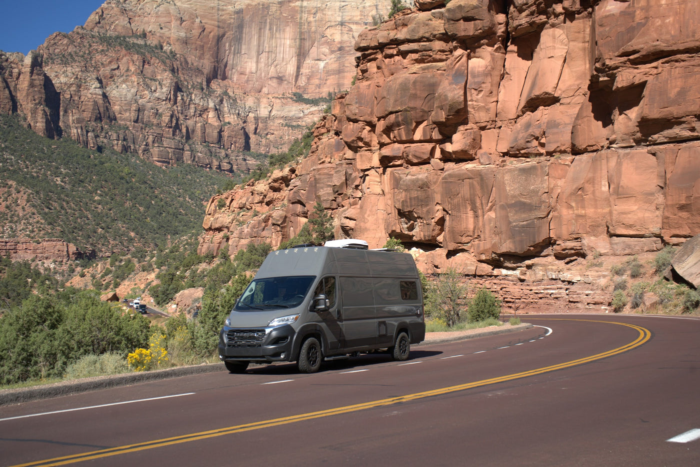 Grey RV rental camper van drives a scenic mountain road through stunning red rock formations. — photo 9