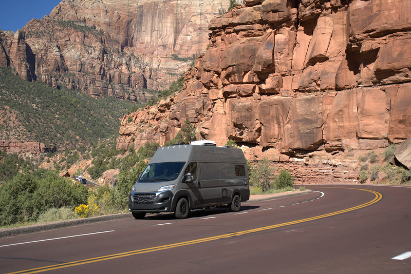 Grey RV rental camper van drives a scenic mountain road through stunning red rock formations. — photo 9