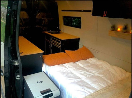 Step into this cozy RV rental: a bed, kitchen, fridge, and charming decor make for ideal mobile living.