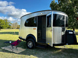 An Airstream Basecamp travel trailer, with its door open and camping gear outside, ready for your next rv rental.