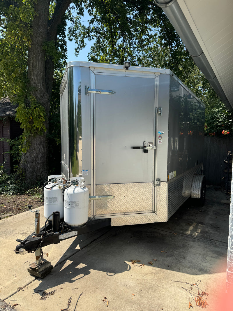 A large, gray enclosed trailer with dual propane tanks sits on a driveway, ideal for RV rental. — photo 4