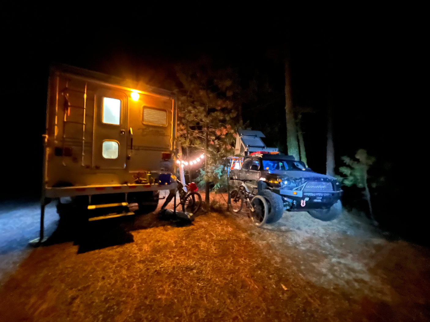 Night setup with an RV rental, an off-road truck, and bikes, perfect for outdoor adventures.