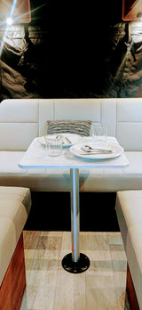 RV rental dinette: Clean white benches, set table with glasses & plates, ready for meals in a modern interior.