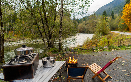 Enjoy your RV rental adventure with outdoor cooking, a warm campfire, and serene river views surrounded by vibrant fall foliage.