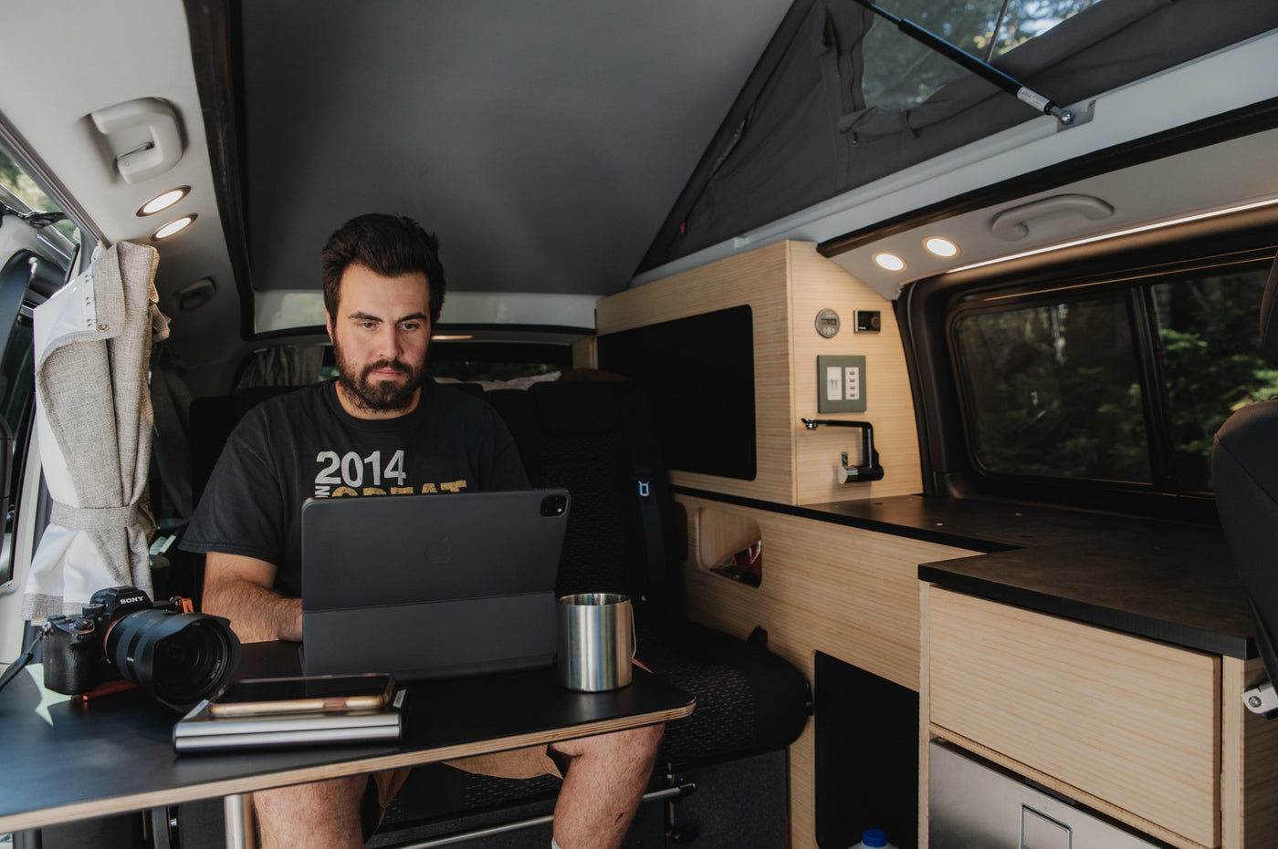  and energy monitor. Ocean view.|Exploring van life: a person in a plaid shirt opens the refrigerator in their RV rental camper van kitchenette by a lake.|Compact RV rental interior featuring a built-in wooden kitchenette with an open mini-fridge and vehicle seating.|This RV rental campervan interior offers a compact kitchen setup with a meal — photo 12