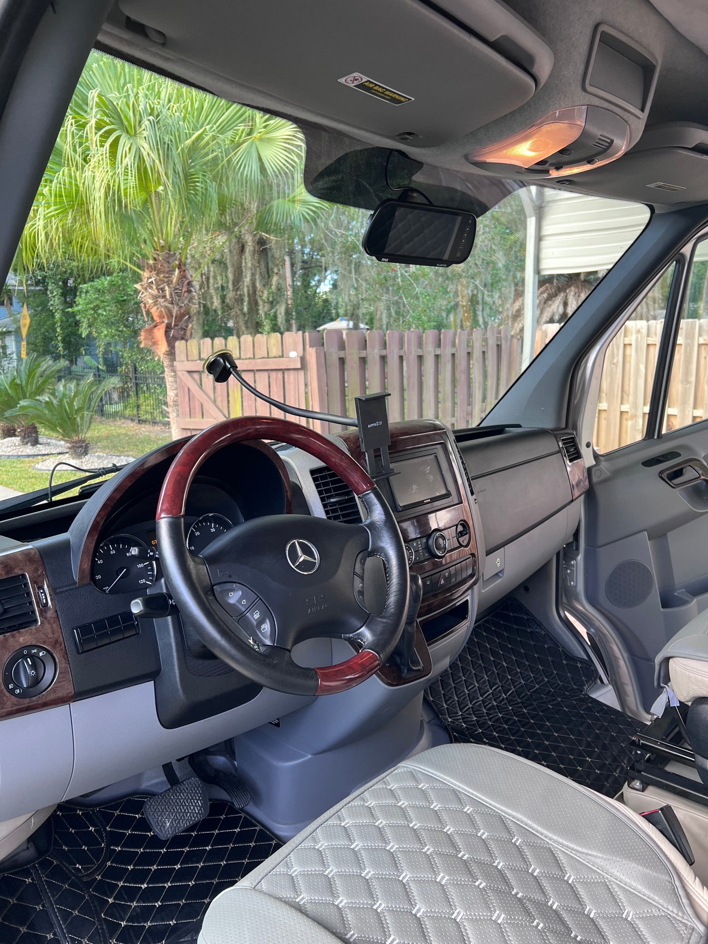 Mercedes Sprinter RV rental: spacious interior with wood-grain dash, custom quilted seats, and modern tech.