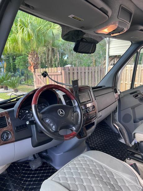 Mercedes Sprinter RV rental: spacious interior with wood-grain dash, custom quilted seats, and modern tech.