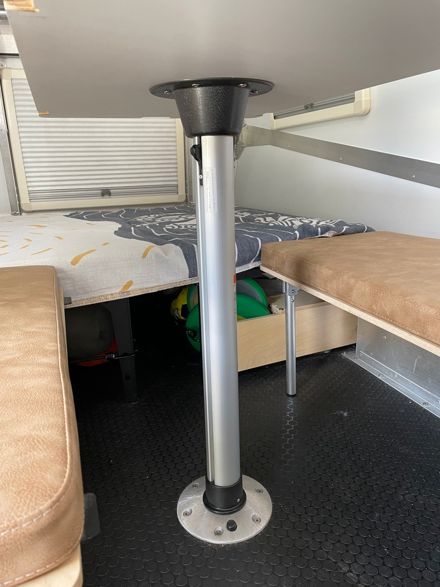 RV rental interior showcasing a versatile dining table, built-in benches with storage, window blinds, and a durable floor.