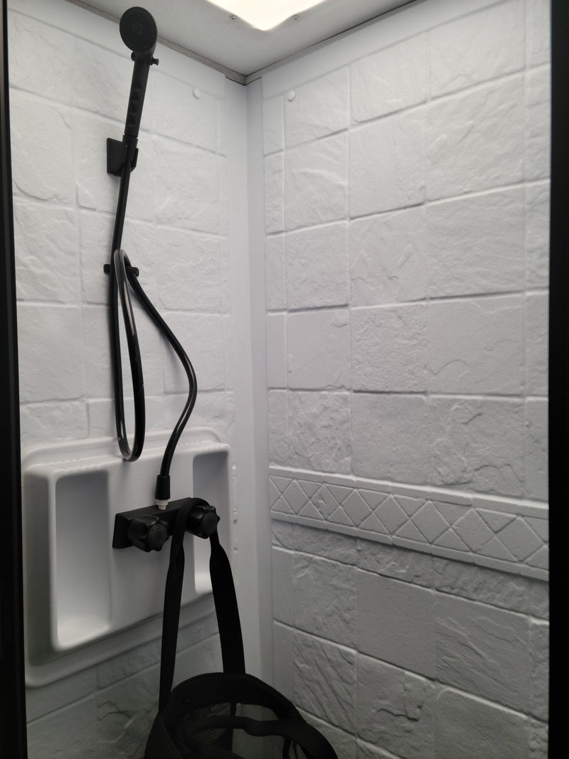 Compact RV rental shower: white textured walls, black handheld showerhead, and controls. Clean, functional bathroom for travel. — photo 9