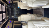 Luxurious RV rental interior: spacious cabin with cream leather seats, wooden floors, accent lighting, and a mounted TV.