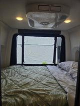 Cozy RV rental bedroom with lake views through a screened window, featuring a comfy bed and AC unit.