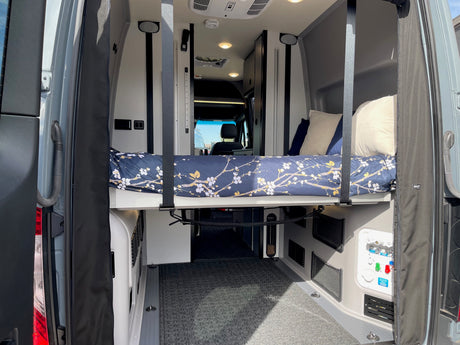 Inside an RV rental: A clever raised bed over a large cargo space, equipped with controls, perfect for van life adventures.