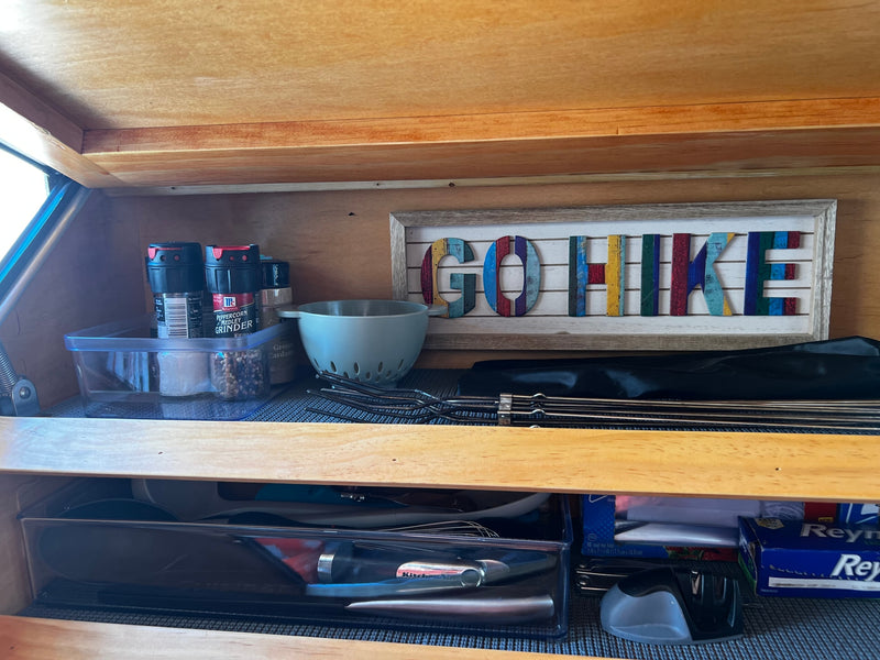 Well-organized kitchen in an RV rental, featuring McCormick spices, grilling skewers, utensils, and a "GO HIKE" sign. — photo 15