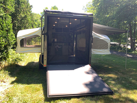 Explore nature with this unique RV rental: a converted cargo trailer featuring pop-out tents and an awning for versatile camping.