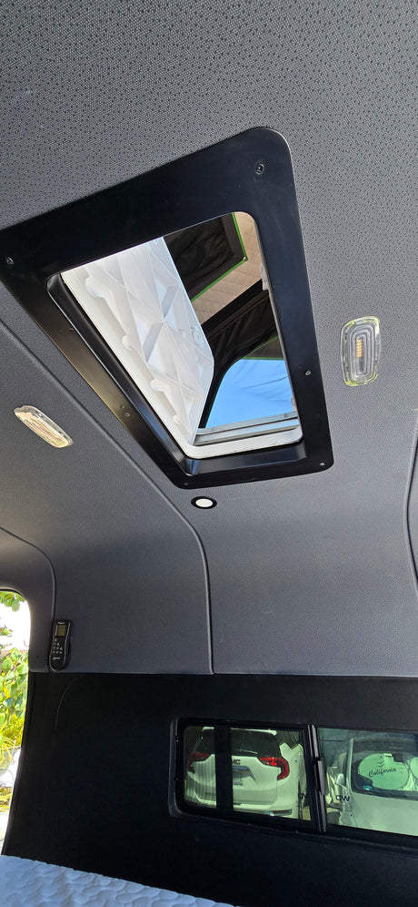 Inside your RV rental: a bright camper van ceiling with an open roof vent for fresh air and natural light.