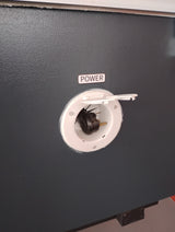 RV rental external power hookup: black plug in white recessed power receptacle on dark gray wall, labeled 'POWER'.